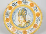 un gros plan sur une assiette jaune et bleue sur laquelle figure l'image d'une femme