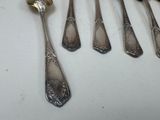 five spoons and a fork on a white table