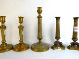 four brass candlesticks are lined up on a white surface