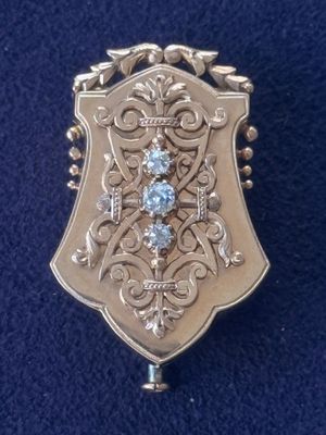a close up of a silver and blue broochle on a blue cloth