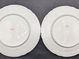 two white plates with designs on them sitting on a table