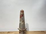 a stone obelisk on a wooden table with a white background