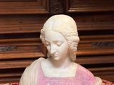une statue représentant une femme assise sur une nappe rouge et dorée