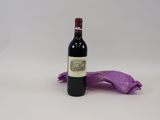 une bouteille de vin posée sur une table à côté d'un sac violet
