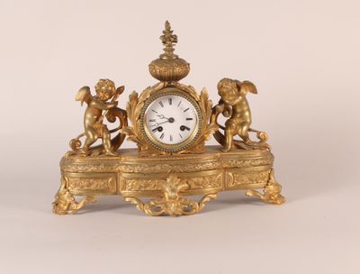 une horloge en or ornée d'anges, posée sur une table
