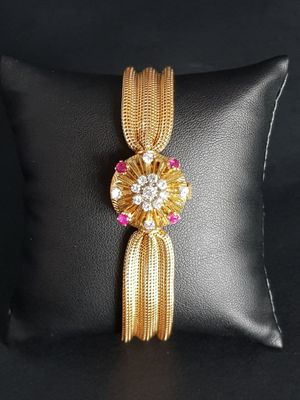a close up of a gold and pink bracelet on a black pillow
