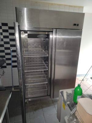 un réfrigérateur en acier inoxydable dans une cuisine au sol en damier