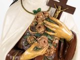 a statue of a woman holding a cross and a bunch of flowers