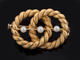 a close up of a gold and pearl broochle on a black surface