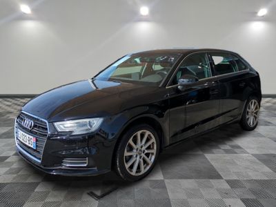 Une Audi noire est garée dans une grande pièce au sol carrelé.