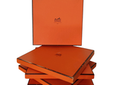 trois boîtes orange sont empilées les unes sur les autres sur une surface blanche