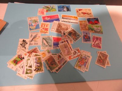 de nombreux timbres différents posés sur une feuille de papier bleue posée sur une table