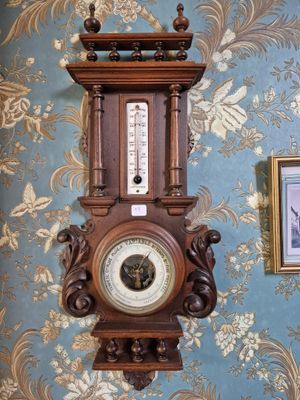 une horloge accrochée au mur dans une pièce, avec un mur tapissé derrière elle