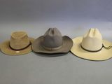 three hats are lined up on a table with a gray background