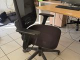 a black office chair sitting in front of a computer desk
