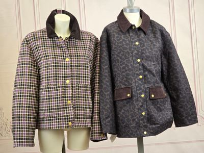 pair of coats on mannequins in front of wallpapered wall