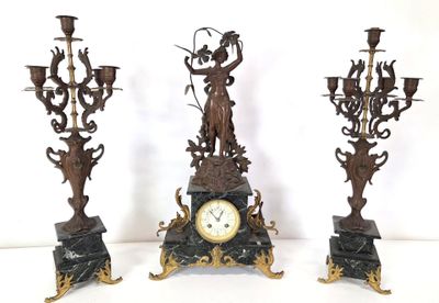 three different types of candlesticks and a clock on a table