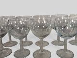 six clear wine glasses lined up in a row on a white surface