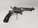 un vieux revolver posé sur une surface blanche, avec une crosse noire