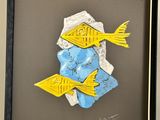 two yellow and blue fish on a piece of paper in a black frame