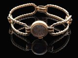 une photo d'un bracelet en or avec une montre, sur un fond noir