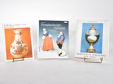 three books on a white surface with a vase and a vase on a stand