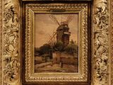 a painting of a windmill in a golden frame on a wall