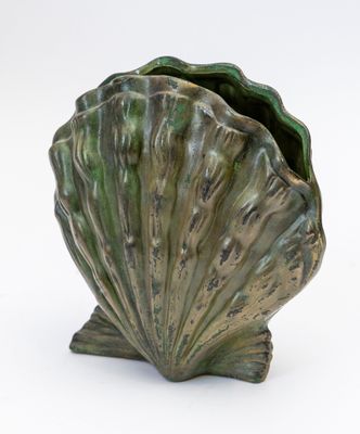 a large green shell shaped vase on a white surface
