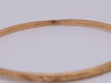 a close up of a gold bang bracelet with a diamond in the middle