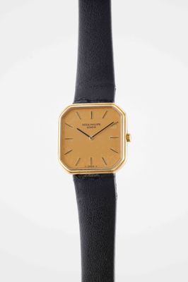 a close up of a gold watch on a black leather strap