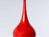 un vase rouge posé sur une table blanche
