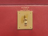 the handle of a red bag with a gold plate on it