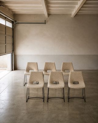 Plusieurs chaises sont alignées dans une grande pièce dotée d'une porte coulissante en verre.