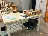 une table avec une chaise et un sac posé dessus, dans une pièce