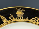 une assiette noire et dorée sur laquelle figure l'image d'un homme et d'une femme