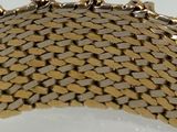 a close up of a gold bracelet on a white surface