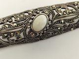 a close up of a silver bracelet with a white stone on it