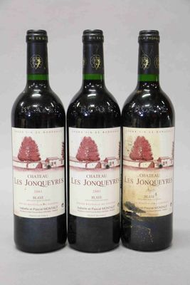 trois bouteilles de vin rouge sont alignées sur une surface blanche