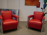 two red chairs in a room with a painting on the wall