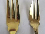 gold plated forks and spoons on a white surface