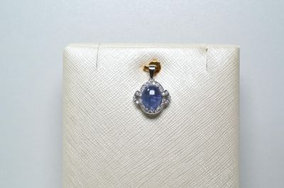 un gros plan d'un pendentif en forme de diamant bleu et blanc posé sur une carte blanche