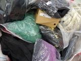 un tas de vêtements dans un sac en plastique posé par terre