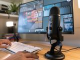 une personne assise à un bureau, avec un micro et un clavier