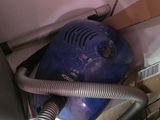 un sèche-cheveux bleu posé par terre à côté d'une pile de cartons