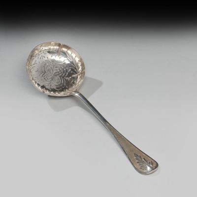 une cuillère en argent posée sur une surface blanche, sur fond noir