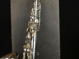 a close up of a silver saxophone with a black background