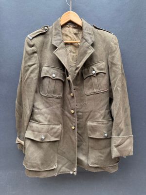 une vieille veste militaire suspendue à un cintre sur un mur bleu