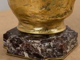 a gold vase sitting on top of a marble base