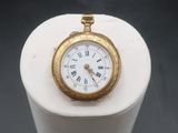 a gold pocket watch sitting on a white pedestal