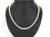 a white pearl necklace on a black mannequin